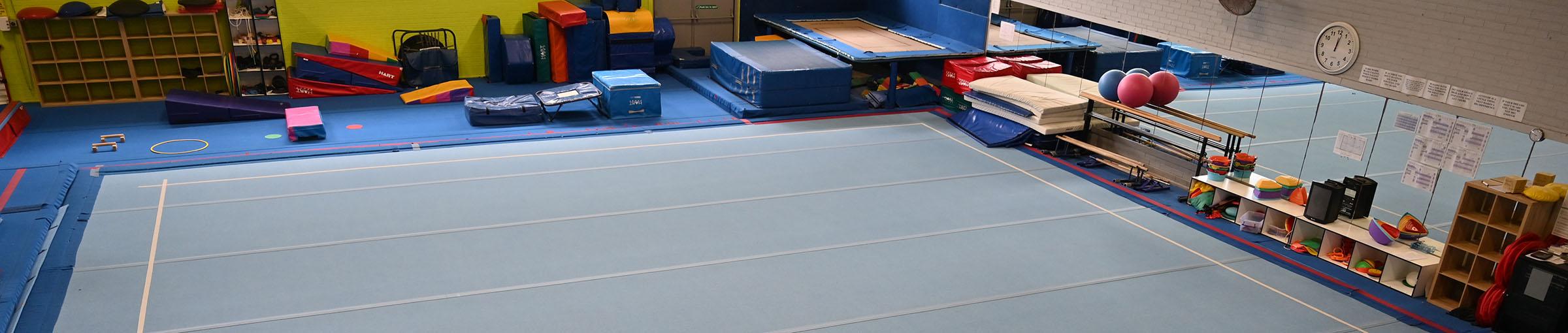 Soft floor of gymnasium surrounded by mirrors and equipment.