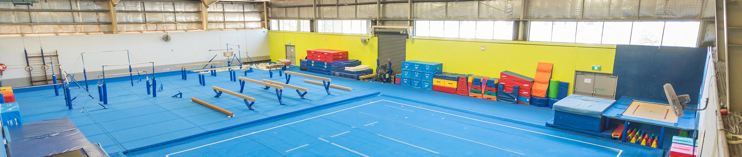 Image of large indoor gymnastics centre with beams and foam mats